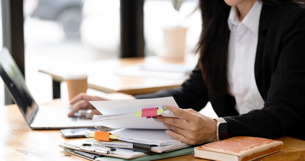 Business woman's hands meticulously reviewing a stack of documents,